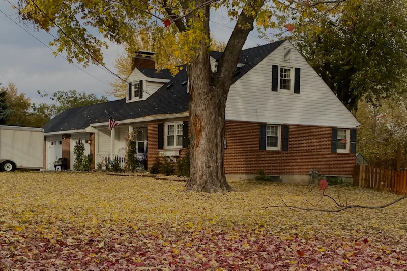Brick ranch house with white gable siding behind a maple in fall color