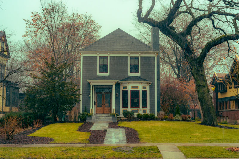 Gray two-story house with white trim behind bare trees