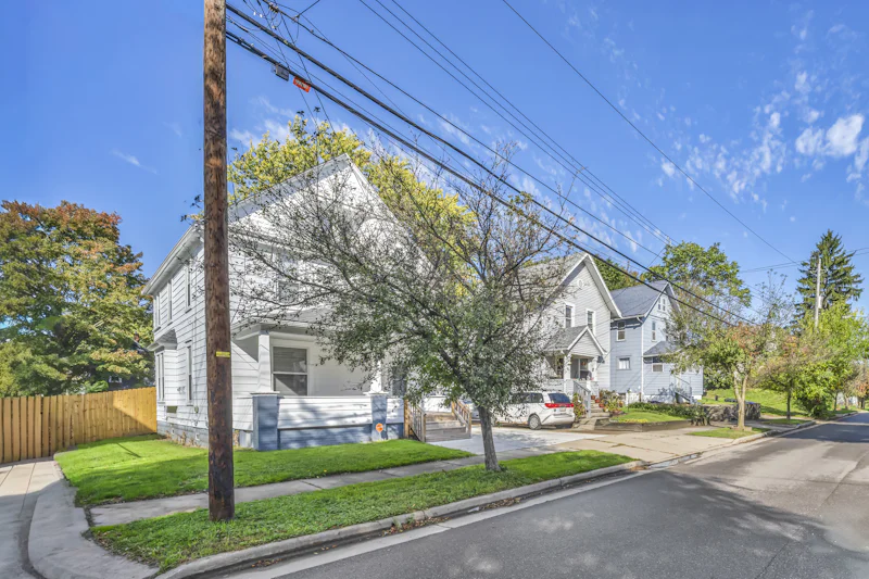 White house with a porch beside a blue house on a residential street