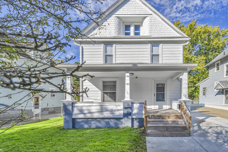 White two-story house with a front porch and a painted block foundation